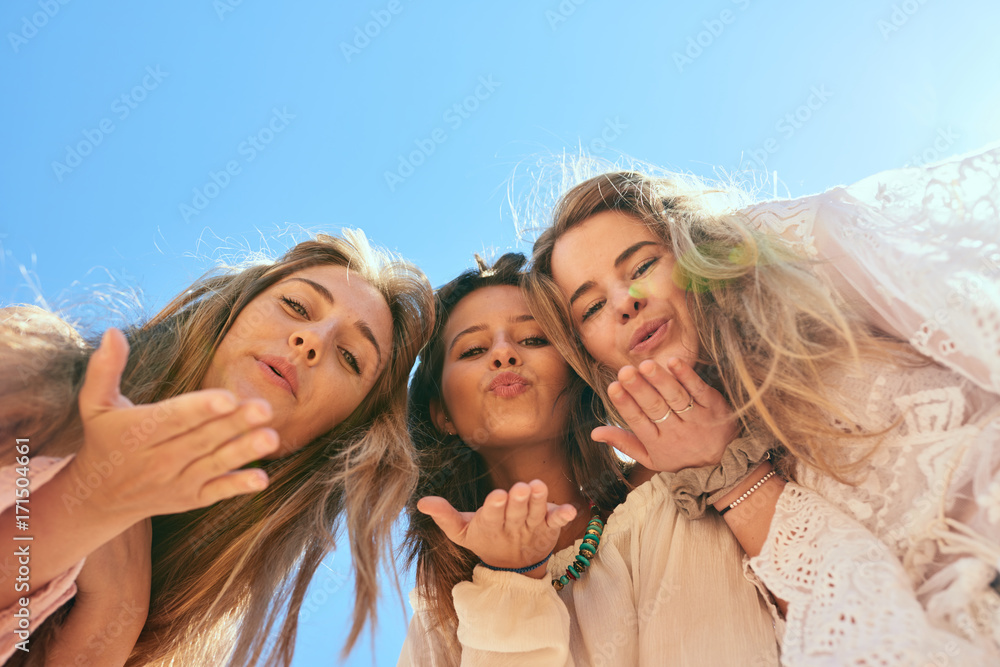 Three beautiful friends making air kisses at camera Three beautiful friends making air kisses at camera