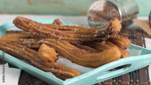 Traditional churros with hot chocolate dipping sauce on wooden counter top.