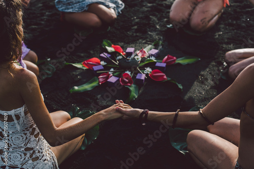 Women on the beach join hands around the flower mandala
