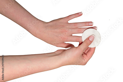 Female hands are washing off the nail polish with a cotton disc, isolated on a white background