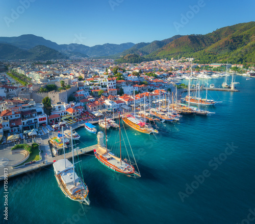Aerial view of boats and beautiful architecture at sunset in Marmaris, Turkey. Colorful landscape with boats in marina bay, sea, city, mountains. Top view from drone of harbor with yacht and sailboat photo