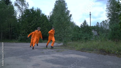 Prisoners in orange uniform or robe escaped from prison. Men runs from police or guard