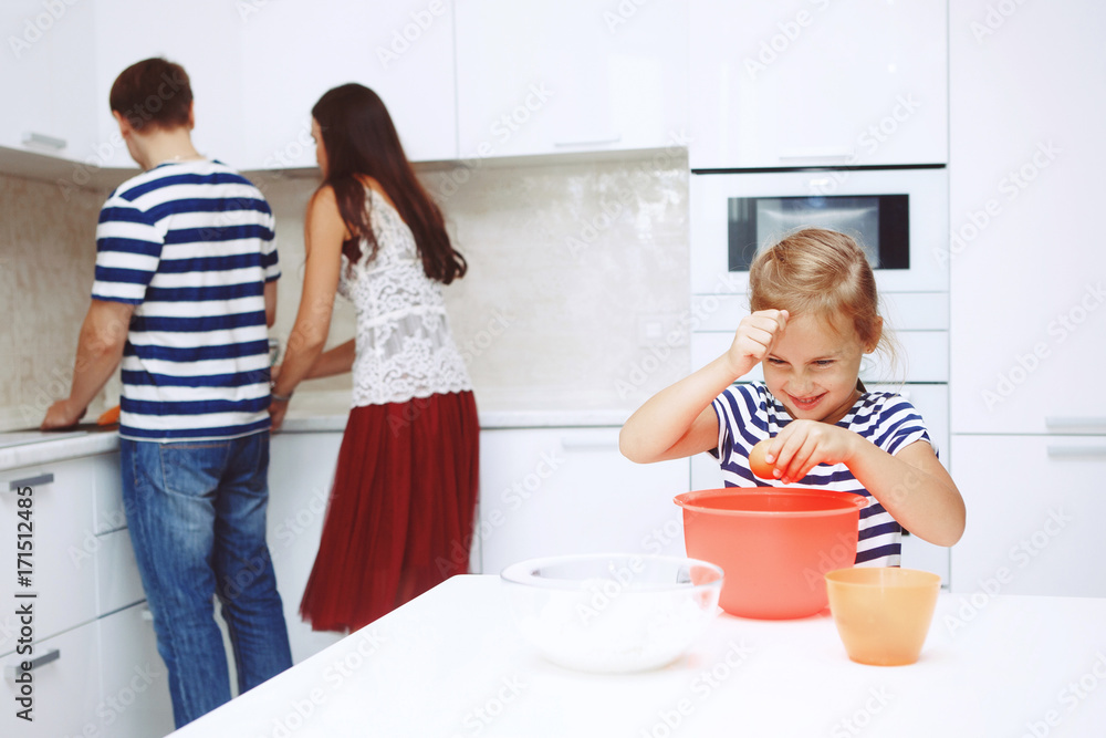 Adorable happy family makes cakes together on your white kitchen. Adorable happy family makes cakes together on your white kitchen.