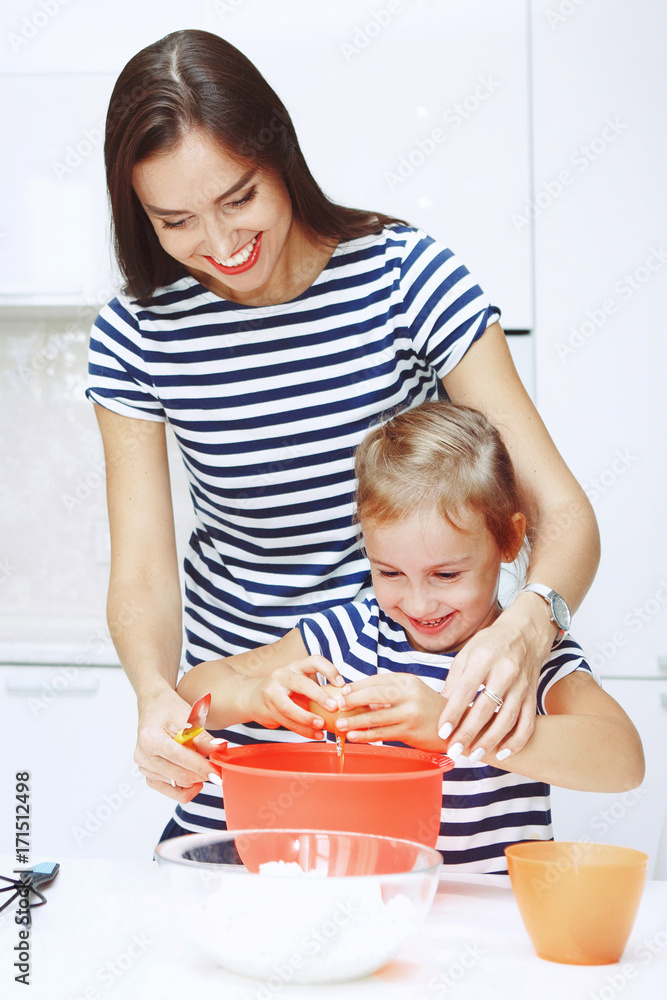 Adorable happy family makes cakes together on your white kitchen. Adorable happy family makes cakes together on your white kitchen.