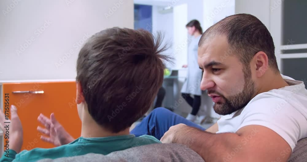 Family leisure at home apartment 4k video. Father talks to son child, mother in kitchen at background. Back view of heads. Parents love Family leisure at home apartment 4k video. Father talks to son child, mother in kitchen at background. Back view of heads. Parents love