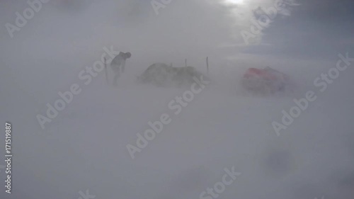 A shot of a powerful blizzard. The man is outside his tent while the blizzard is occurring.