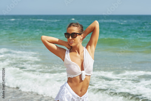 The young woman at the seaside in a white blouse and sunglasses