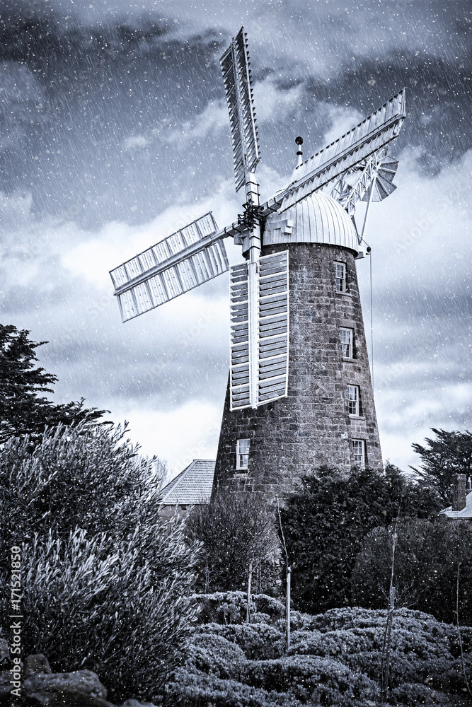 Windmill in the countryside covered in artificial rain and snow.