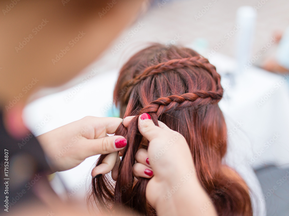 Fototapeta premium the stylist weaves the female braids on the head