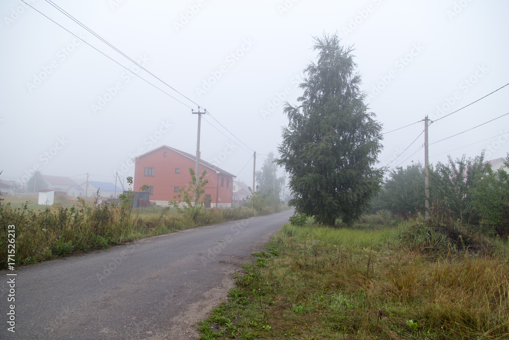 the road in the village in the fog in the morning