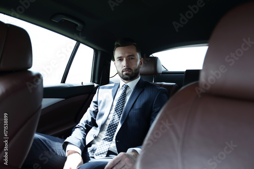 Successful businessman sitting in the back seat of a car © ASDF