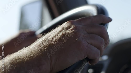 Detail of  truck driver's hands on wheel as he drives on a warm summer day. Interior, hand-held real time 4K