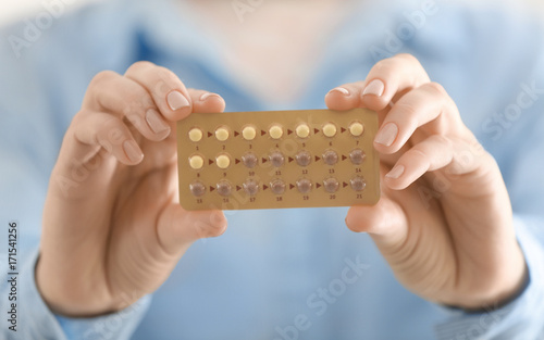 Woman holding hormonal pills, closeup
