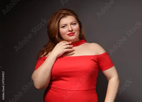 Overweight woman in beautiful red dress on grey background
