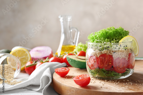 Cooked quinoa served with fresh vegetables and lemon in glass jar on kitchen table