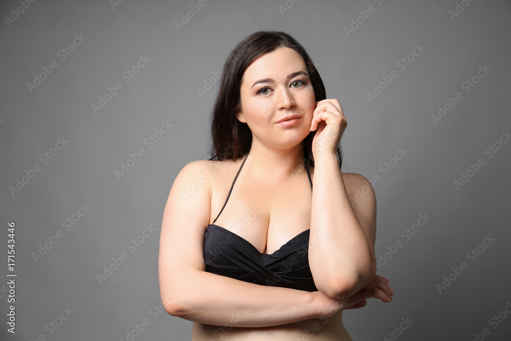 Fototapeta premium Beautiful overweight woman in black bikini on grey background