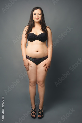 Beautiful overweight woman in black bikini on grey background © Africa Studio