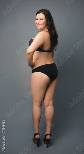 Beautiful overweight woman in black bikini on grey background © Africa Studio