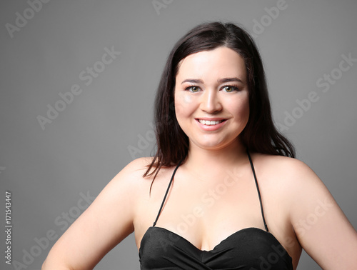 Beautiful overweight woman in black bikini on grey background