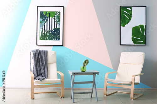 Modern room design with framed pictures of tropical leaves and two chairs