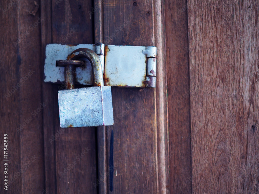 Old rusty grey shiny iron steel lock and hinge, on Thai old local traditional style wooden door, close up Old rusty grey shiny iron steel lock and hinge, on Thai old local traditional style wooden door, close up