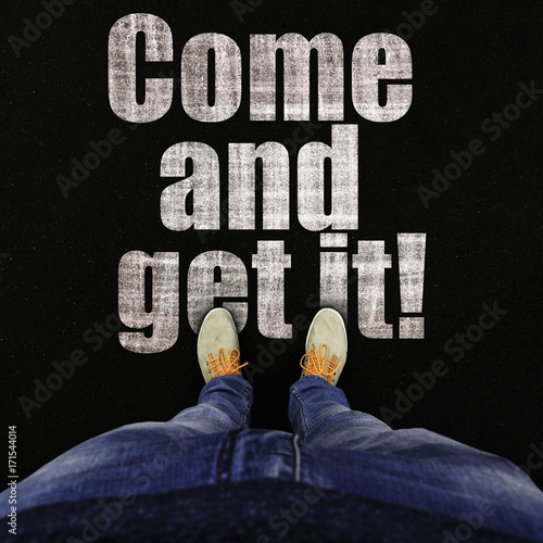 Top view on legs in sports sneakers and jeans on asphalt with text come and get it