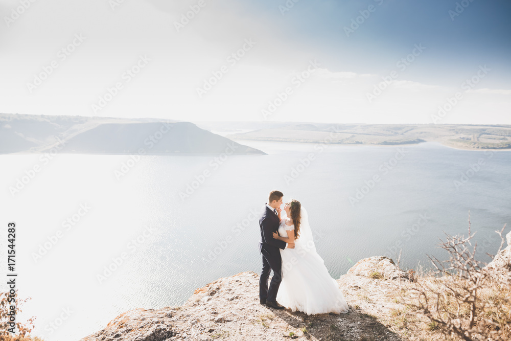 Happy and romantic scene of just married young wedding couple posing on beautiful beach