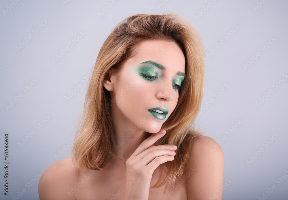 Naklejka premium Young woman with bright green makeup on color background
