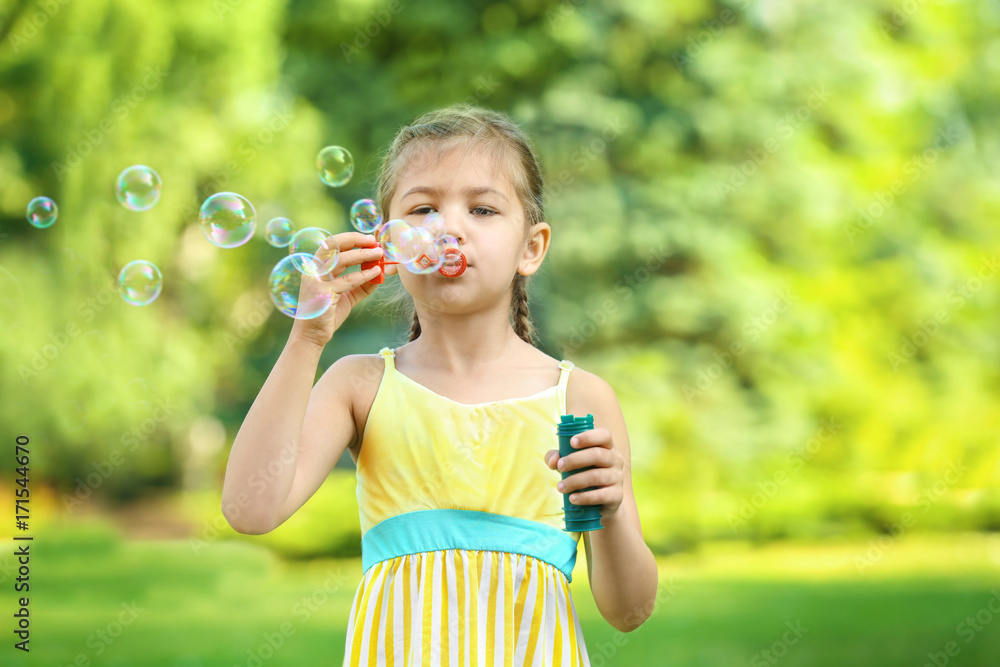 Cute little girl blowing soap bubbles outdoors Cute little girl blowing soap bubbles outdoors