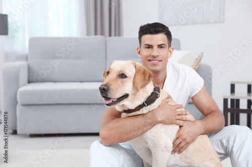 Young man resting with yellow retriever at home