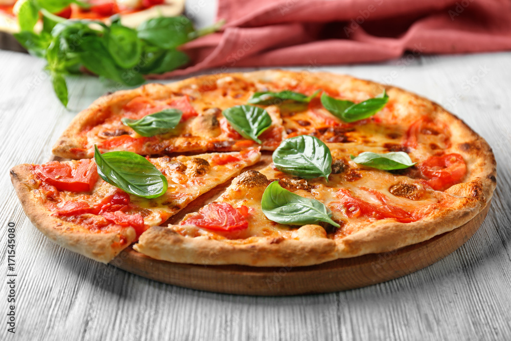 Delicious pizza with tomatoes and fresh basil on kitchen table