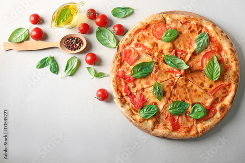 Composition with pizza, oil, cherry tomatoes and fresh basil on light background
