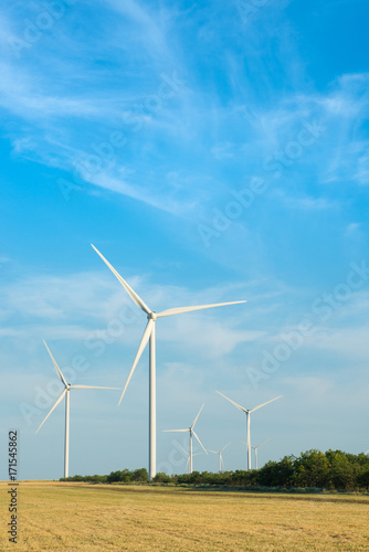Wind mill in field with blue sky. Power and energy. © Viktoria
