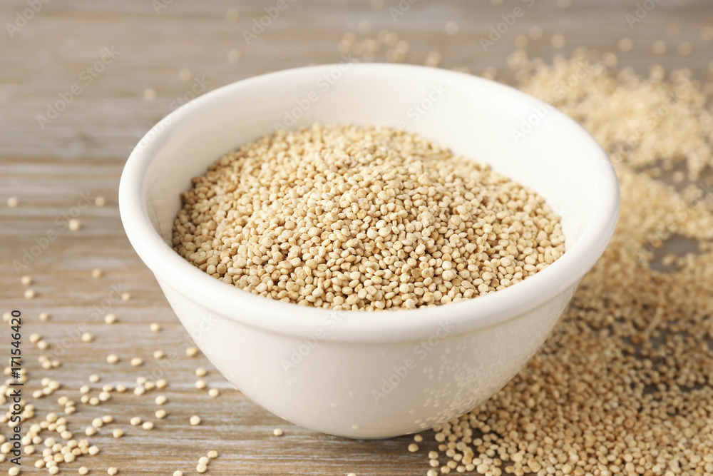 White quinoa in ceramic bowl on wooden background White quinoa in ceramic bowl on wooden background