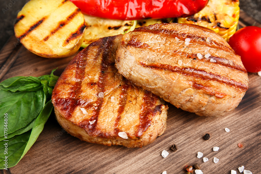 Composition with tasty grilled steaks on table, closeup Composition with tasty grilled steaks on table, closeup