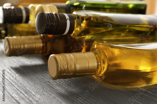 Bottles with different cooking oil on wooden background