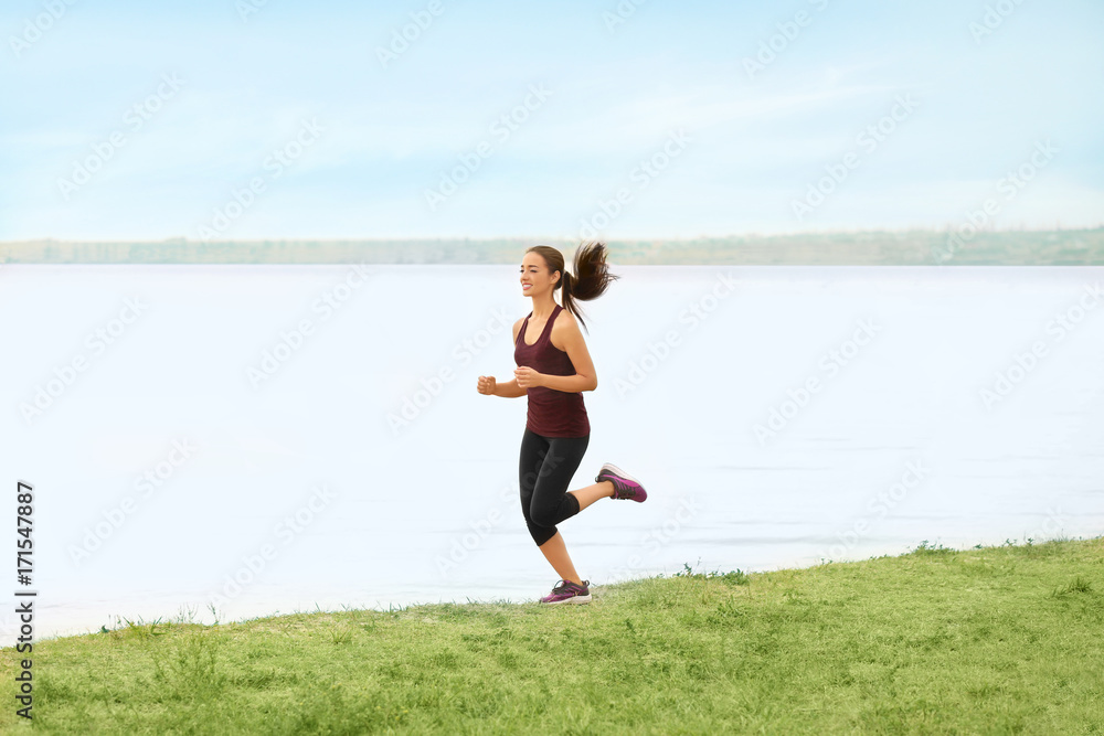 Young sporty woman running on river shore Young sporty woman running on river shore