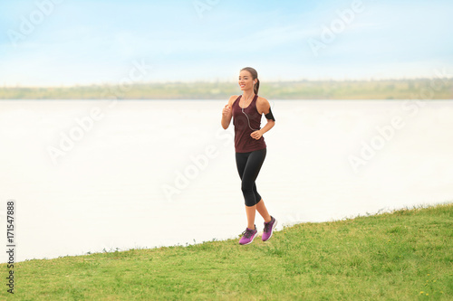 Young sporty woman running on river shore