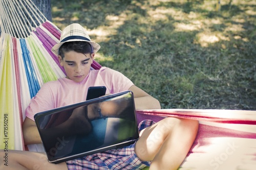 child with mobile phone in the hammock in summer