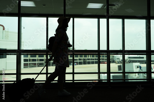 Silhouette of woman hanging camera and luggage for traveling at the airporttravel concept, people in the airport