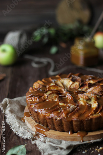 Apple pie with salted caramel on a wooden background
