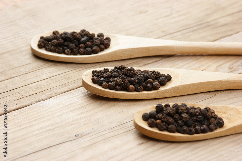 Black pepper in wooden spoon on the old board Black pepper in wooden spoon on the old board