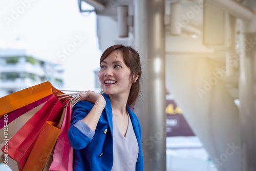 asian woman shopping smile and holding credit card and shopping bag with shopping mall background, consumerism, sale and people online concept