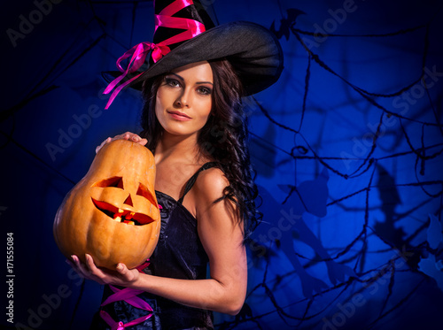 Halloween pumpkin in witch woman hands. Young mother preparing for children's holiday on black bat on net. Family holiday. photo