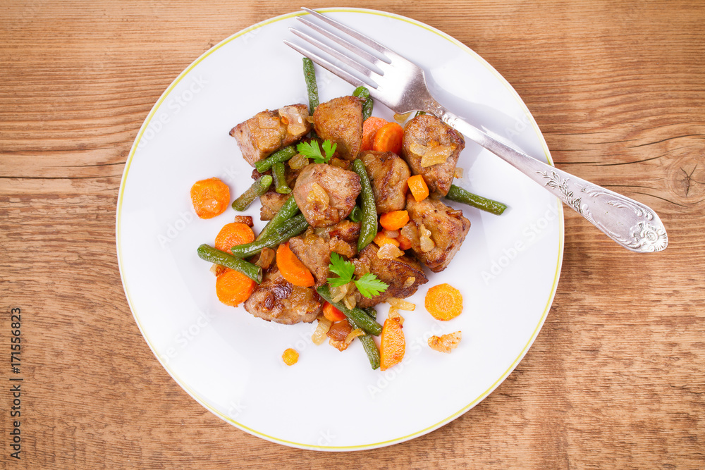 Beef liver with vegetables: carrot, onion and green beans on white plate. Top, overhead, above view, horizontal Beef liver with vegetables: carrot, onion and green beans on white plate. Top, overhead, above view, horizontal