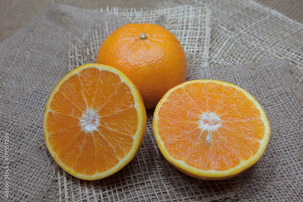 Orange, half of orange,with oranges on the wooden table on the sack background Orange, half of orange,with oranges on the wooden table on the sack background