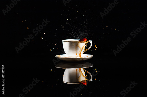 Coffee splashes in white cup on black background