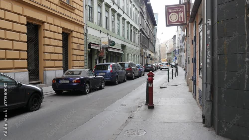 White SUV driving through narrow passage street in the city. Car moving through alley White SUV driving through narrow passage street in the city. Car moving through alley