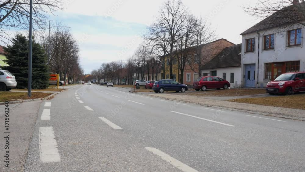 Car passing by on empty small town street road. Vehicle driving in suburban area Car passing by on empty small town street road. Vehicle driving in suburban area
