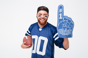 Excited man fan wearing fan glove holding rugby ball.